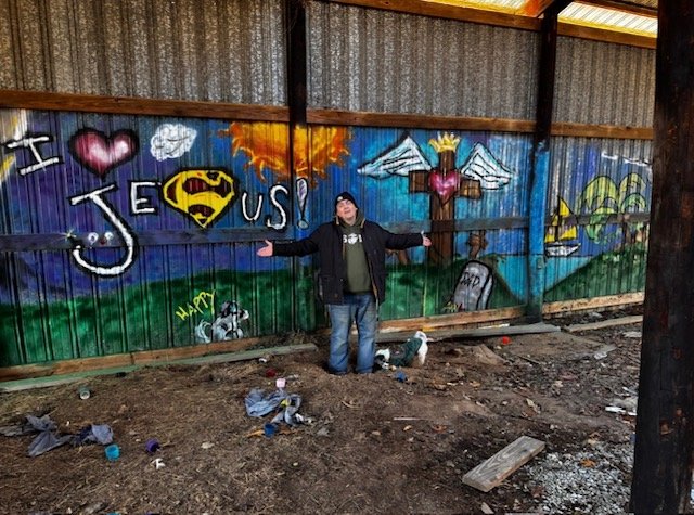 Matthew Wayne standing proudly in front of his completed wall mural